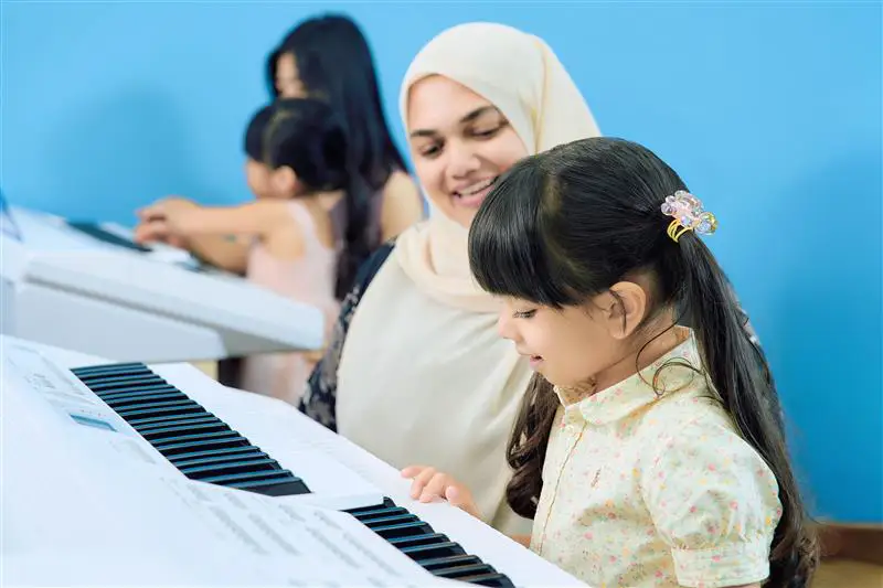 Mother supporting her child during a Yamaha Music School piano class for young learners
